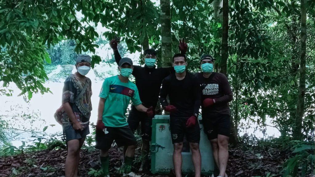 Fünf Männer im Regewald Borneos vor Orang-Utan-Transportbox
